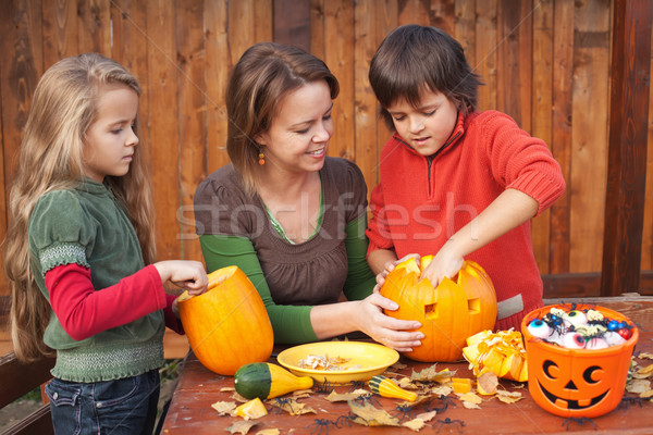 Woman helping kids to carve jack-o-lanterns Stock photo © ilona75