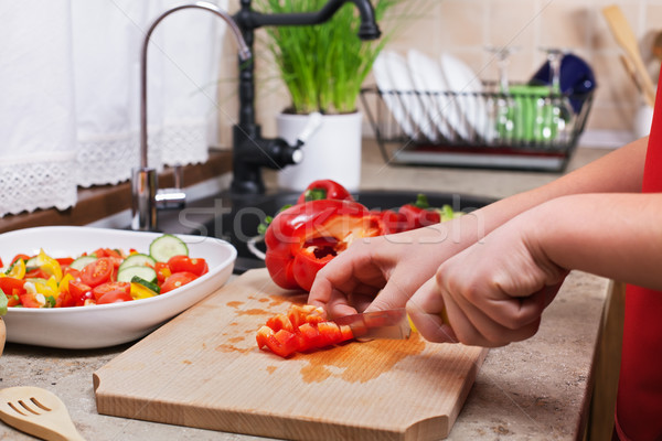 Child hands chopping a red bellpepper for a fresh vegetables sal Stock photo © ilona75