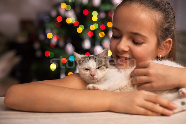 Stock photo: Young girl with her rescued kitten in front of the xmas tree at 