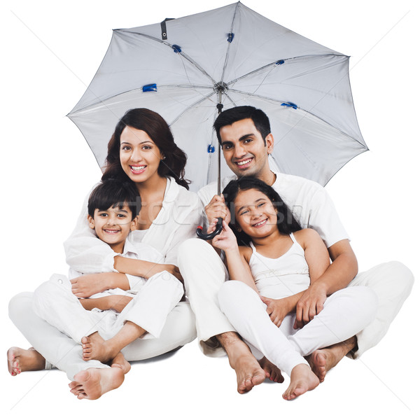 Portrait of a happy family sitting under an umbrella Stock photo © imagedb