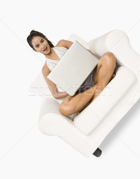 Kadın oturma koltuk dizüstü bilgisayar kullanıyorsanız gülümseme dizüstü bilgisayar Stok fotoğraf © imagedb
