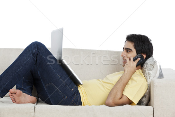 Man talking on a mobile phone and using a laptop at home Stock photo © imagedb