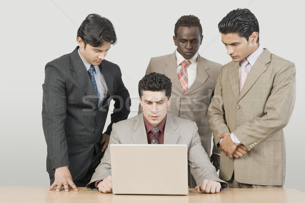 Drei Geschäftsleute schauen Kollege mit Laptop Business Stock foto © imagedb