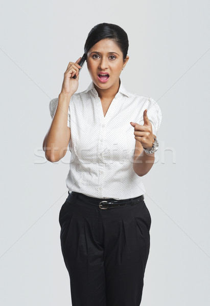 Businesswoman talking on a mobile phone and pointing Stock photo © imagedb