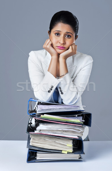 Businesswoman leaning on a stack of files and looking worried Stock photo © imagedb