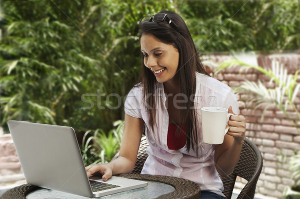 Mulher potável café usando laptop internet laptop Foto stock © imagedb