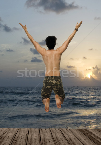 Vue arrière jeune homme sautant joie pier plage [[stock_photo]] © imagedb