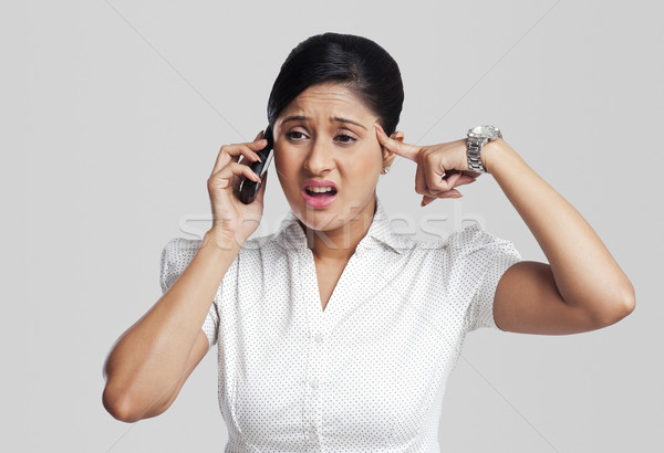 Stock photo: Businesswoman looking upset while talking on a mobile phone