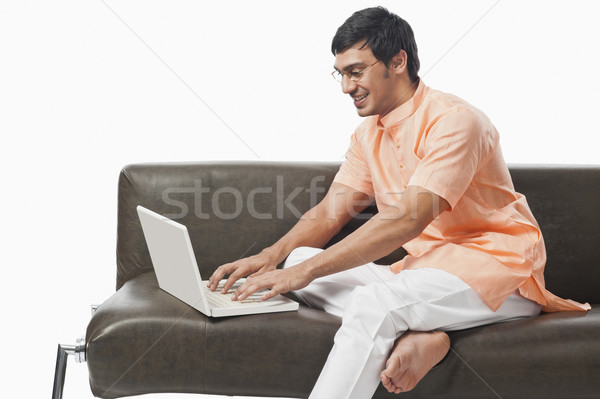 Bengali man using a laptop on the couch Stock photo © imagedb