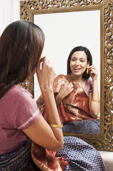 Reflection of a woman in mirror trying a sari and earring on herself Stock photo © imagedb