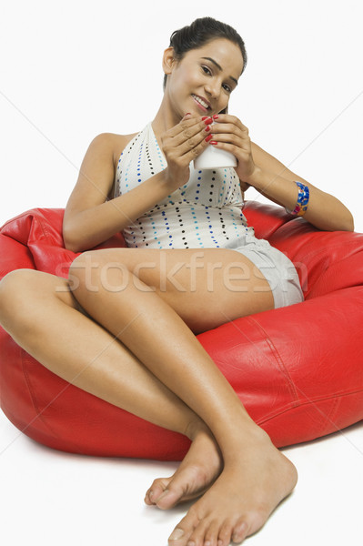 Kobieta posiedzenia bean bag kubek kawy uśmiech Zdjęcia stock © imagedb