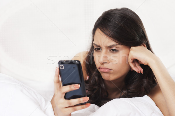 Kobieta sms telefonu komórkowego patrząc smutne sypialni Zdjęcia stock © imagedb