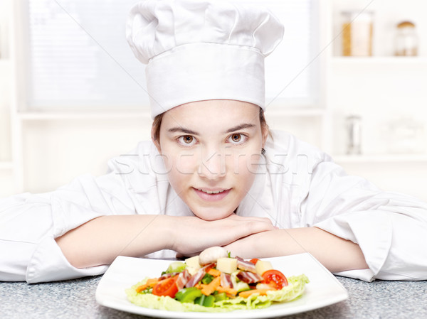 Stock photo: pretty young chef and hers plate of a delicious salad in kitchen