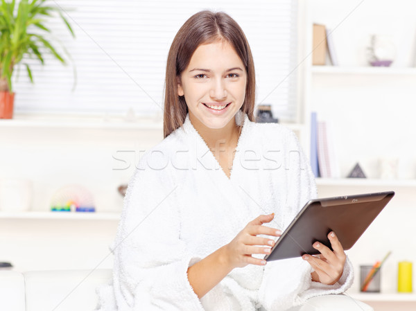girl in bathrobe at home with touch pad Stock photo © imarin