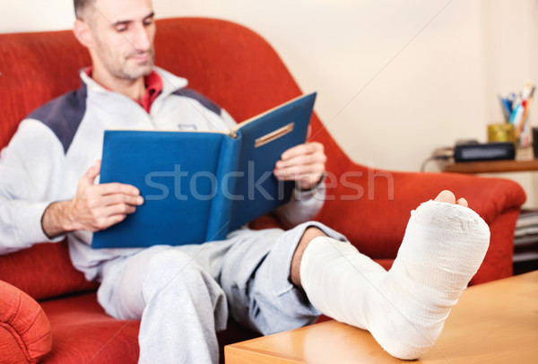 Om picior rupt canapea acasă lectură carte Imagine de stoc © imarin