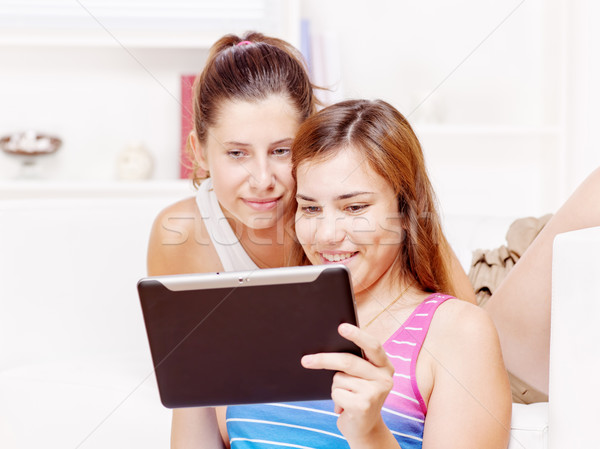 Stock photo: Two happy teenage girls using touchpad computer