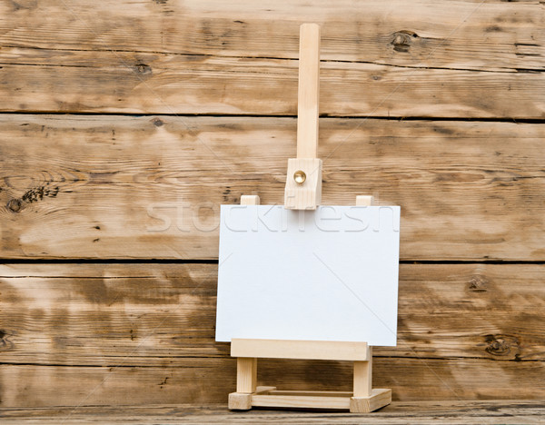 Wooden easel with clean paper on old wooden table Stock photo © inxti