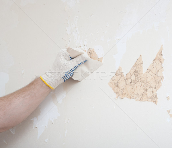 Stock photo: Hand removing wallpaper from wall 