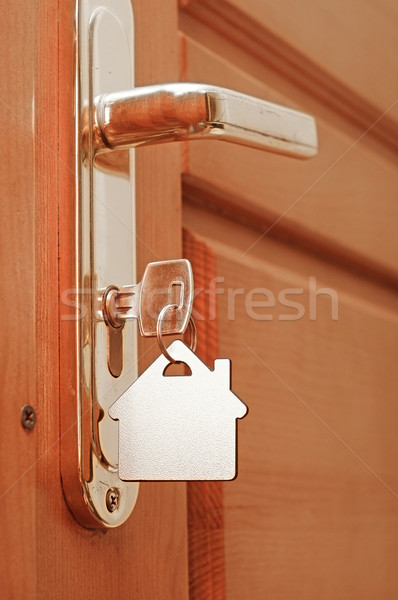 House key on a house shaped keyring in the lock of a door  Stock photo © inxti