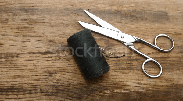 Sewing kit. Scissors with thread and needles on wooden table  Stock photo © inxti