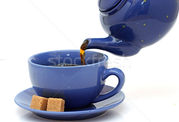 Teapot pouring tea into a cup on a white background Stock photo © inxti