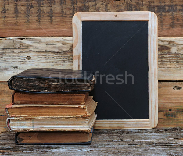 old school books are stacked on a desk in front of a blackboard. Stock photo © inxti