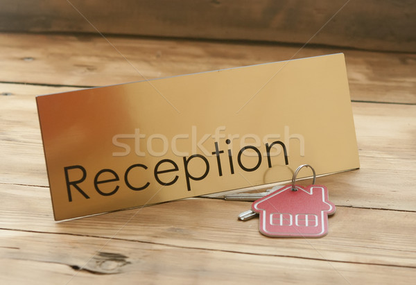 Stock photo: Symbol of the house with silver key on wooden reception desk 