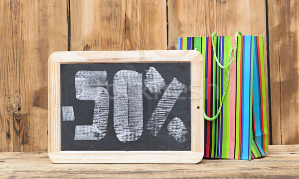 fifty percent written on blackboard with colorful shoping bag Stock photo © inxti