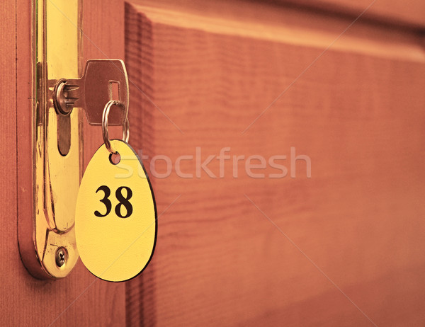 Door handles on wood wing of door and key in keyhole with number Stock photo © inxti