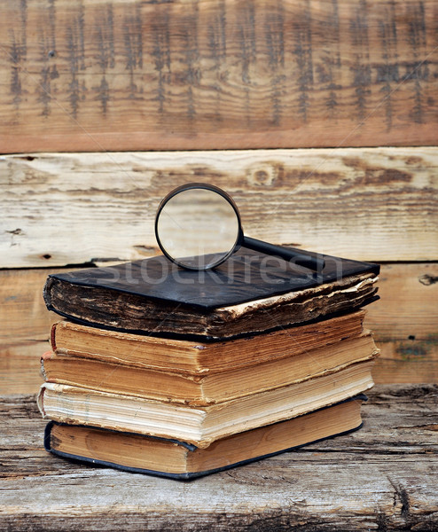 Stack of antique books with magnifying glass on wooden table Stock photo © inxti