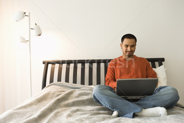 Foto stock: Joven · cama · usando · la · computadora · portátil · jóvenes · hispanos · hombre