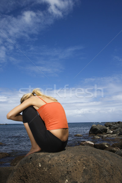 Woman sitting on rocky shore. Stock photo © iofoto