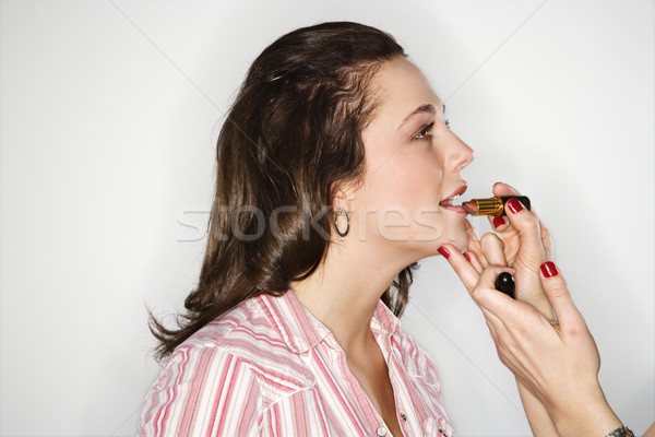 Stock photo: Women putting on lipstick.