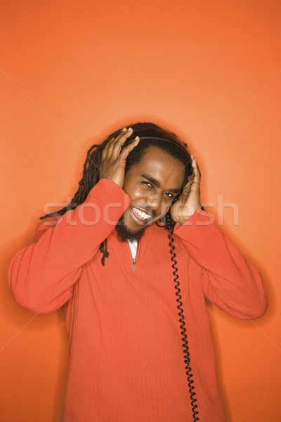 [[stock_photo]]: Homme · casque · écouter · orange · vêtements