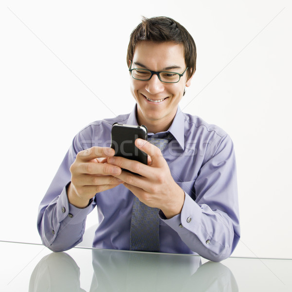 улыбаясь бизнесмен сотового телефона азиатских сидят столе Сток-фото © iofoto