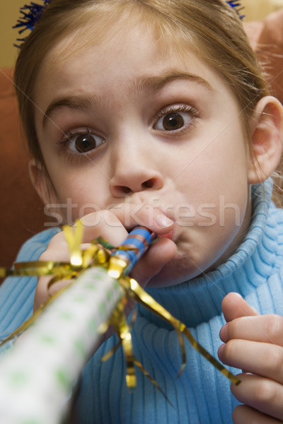 Girl blowing noisemaker. Stock photo © iofoto