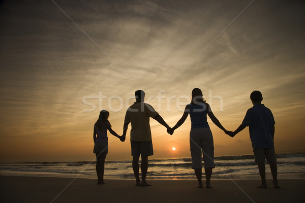 Foto stock: Família · de · mãos · dadas · praia · silhueta · assistindo · pôr · do · sol