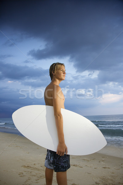 Fiatal férfi szörfös áll tengerpart szörfdeszka Stock fotó © iofoto
