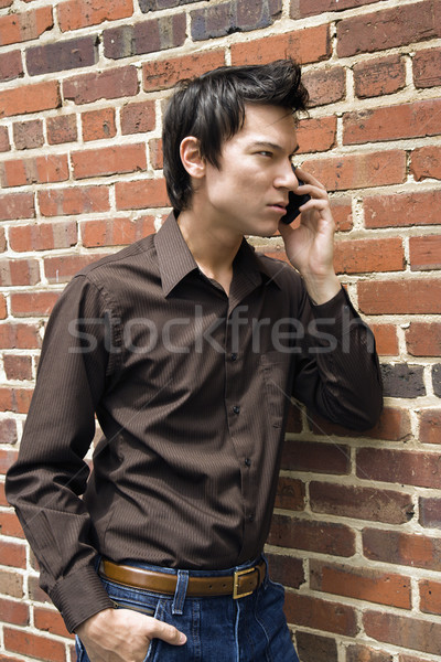 Homem celular jovem asiático parede de tijolos falante Foto stock © iofoto