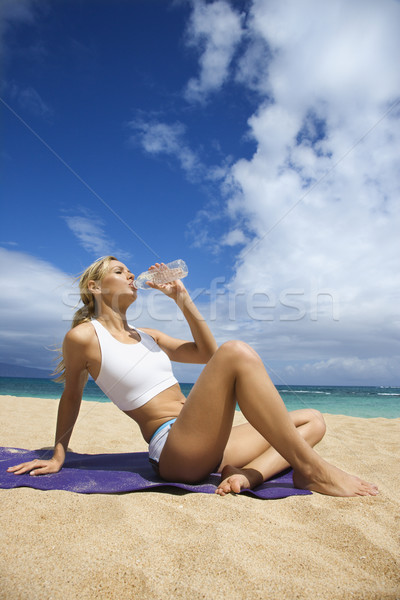 Atrakcyjny młoda kobieta pitnej plaży napojów woda butelkowana Zdjęcia stock © iofoto