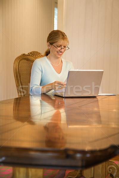Femme regarder ordinateur utilisant un ordinateur portable sourire Photo stock © iofoto