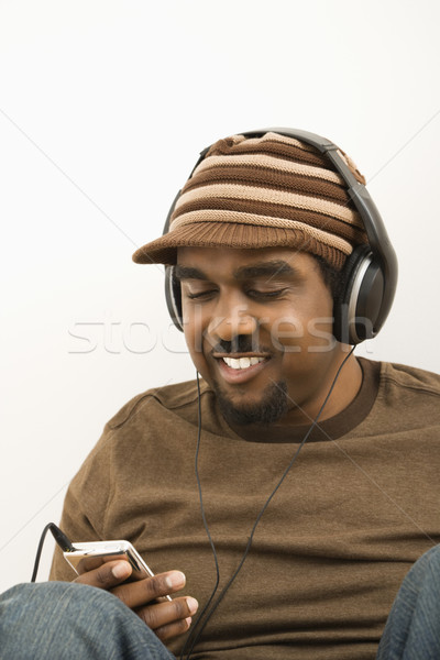 Férfi mp3 lejátszó visel kalap hallgat mosoly Stock fotó © iofoto