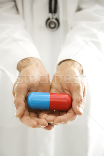 Stock photo: Doctor holding giant pill.