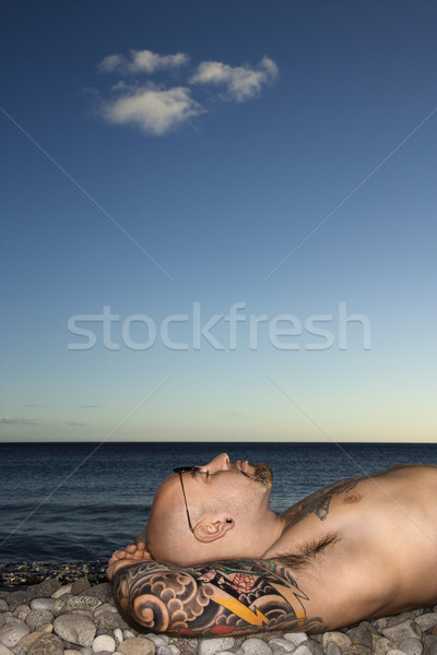 Tattooed Man Lying on Beach Stock photo © iofoto