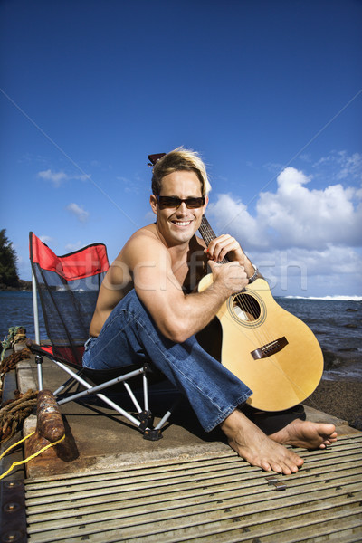 Young Man Sitting Lakeside and Holding Guitar Stock photo © iofoto