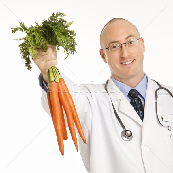 Stock photo: Doctor holding carrots.