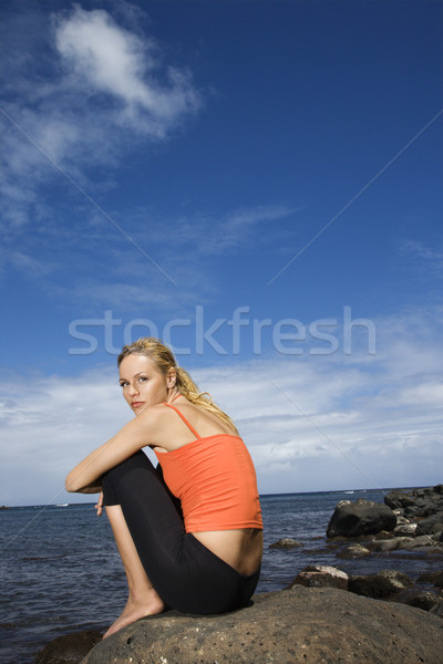 Woman sitting on rocky shore. Stock photo © iofoto