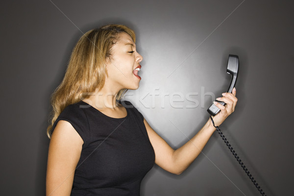 Woman yelling into telephone. Stock photo © iofoto