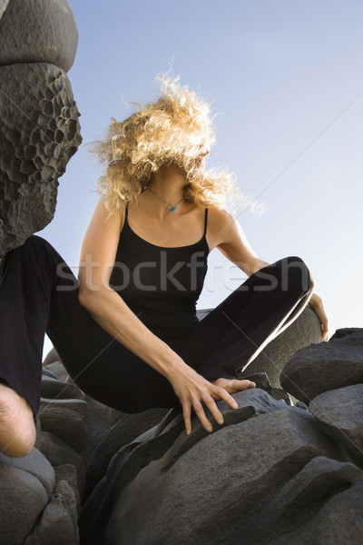 Woman crouching on rocks. Stock photo © iofoto