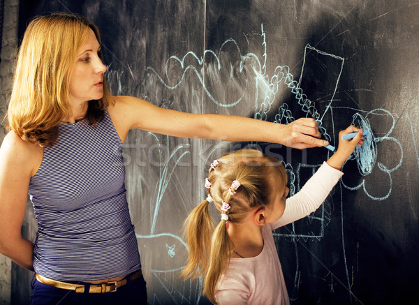 Stock photo: portrait of mature woman teacher with little cute blonde girl pupil writing on blackboard together, 